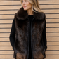 Woman wearing a fur vest against a wooden slat background